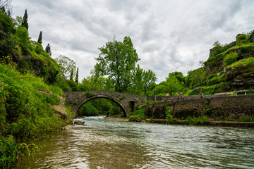 Fototapeta na wymiar Montenegro, Ancient stone bridge called stari most na ribnici over clean river ribnica in green forest podgorica city