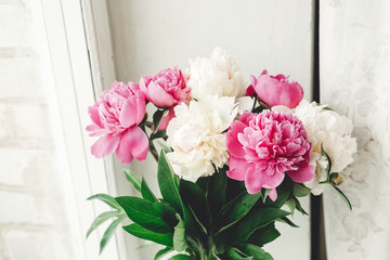 Beautiful pink and white peonies bouquet at rustic old wooden window. Floral decor and arrangement. Gathering flowers. Rural still life, countryside. Copy space
