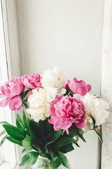 Beautiful pink and white peonies bouquet at rustic old wooden window. Floral decor and arrangement. Gathering flowers. Rural still life, countryside. Copy space