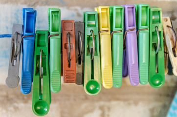 old colored plastic clothespins hanging in a row on the washing line, close up with shallow depth of field and copy space