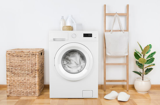 Modern washing machine with basket in laundry room interior