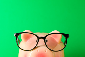 Happy piggy bank with glasses against green background, space for text and closeup. Finance, saving money