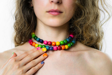 hand with multi-colored nails holding multi-colored wooden beads