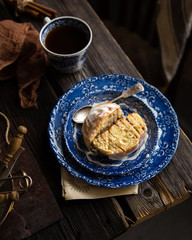 Homemade cinnamon cut roll bun on vintage blue plate with spoon on wooden rustic table