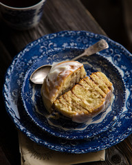 Homemade cinnamon cut roll bun on vintage blue plate with spoon on wooden rustic table