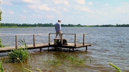 man walks on a pier at the lake in windy weather