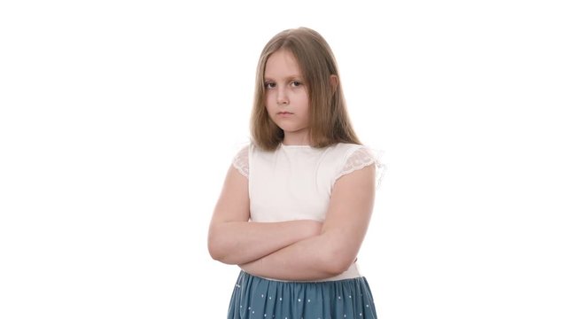 Video portrait of cute upset girl standing with arms folded and looking at camera isolated on white background. Childhood concept. Studio shot of child emotions in 4K definition.