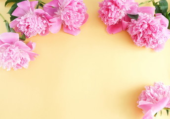 Fototapeta na wymiar Bouquets of pink flowers peonies frame on pale yellow background. top view. copy space