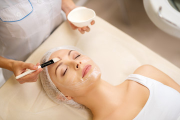Woman closing eyes while dermatologist putting mask on