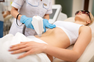 Depilatory master making laser depilation for skinny woman