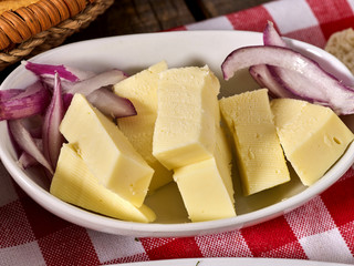 Cheese with onion on plate and checkered napkin in village style.