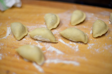 Fototapeta na wymiar Raw dumplings, pierogi on a wood, covered with flour
