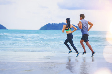Couples runner jogging at the beach with sunset background.