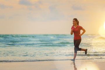 Woman running at the beach with sunset background.