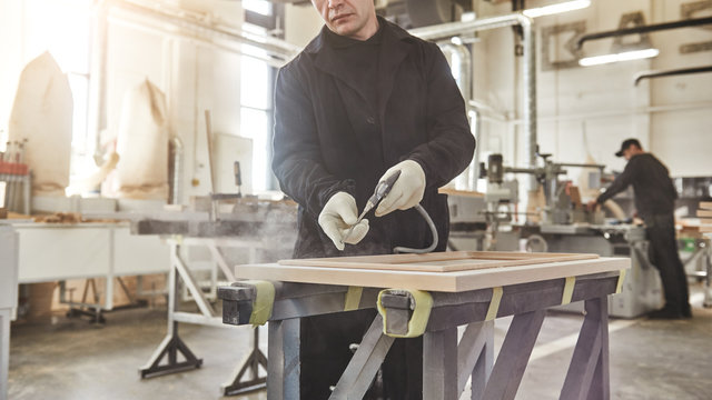 Cropped image of carpenter in uniform working with wood.