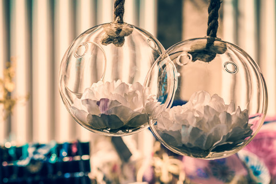 white petals inside round glass recipients hanging