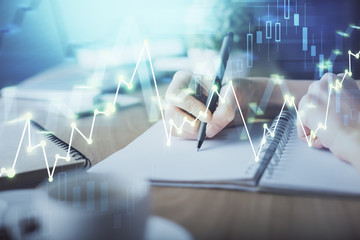 Financial forex graph drawn over hands taking notes background. Concept of research. Multi exposure