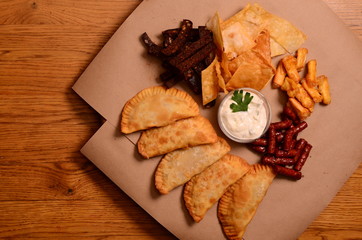Tortilla chips garnished with ground beef, melted cheese, peppers and cilantro leaves in plate on wooden table