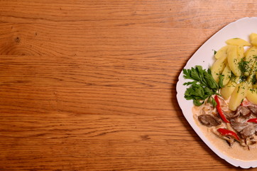 Beef meat stewed with potatoes, carrots and spices in ceramic pot on wooden background