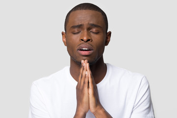 Fototapeta na wymiar African millennial man closed eyes cupped hands and praying