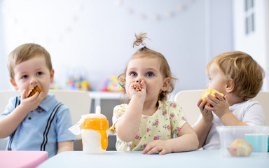Obraz na płótnie Canvas Time to eat in kindergarten. Funny nursery babies have dinner