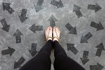 Many Direction Arrow Choices. Gold Shoes Isolated on Concrete Floor,Top View. Woman Standing is...