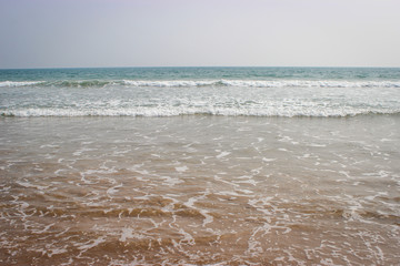 Turquoise blue sea waves on a sandy beach in Goa, India. Beach washed away by the waves.