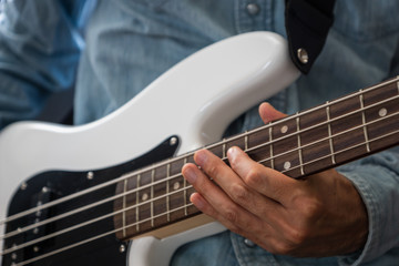 musician playing bass guitar finger style, closeup and selective focus- musical instrument for jazz, rock, blues, funk, hip hop music