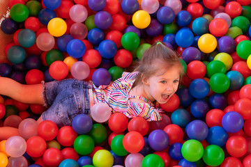 Fototapeta na wymiar Baby girl is playing in playground with colourful balls
