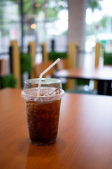 Iced cola in plastic glass with ice on wood table restaurant background.