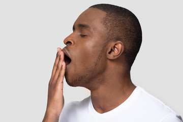 Closeup african male face profile yawning covering mouth with hand