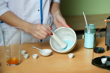 a lab technician conducts chemical experience. the chemist mixes the powder in a mortar by pestle.