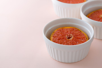Baked Red Graipfruit in white bowl on pink background, copy space, selective focus