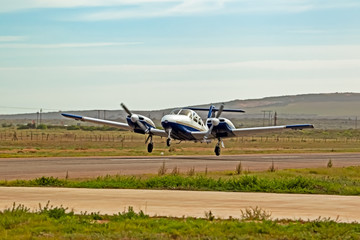 Fototapeta na wymiar Blue and white twin engine aircraft taking off