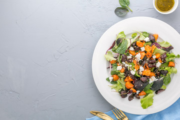 Roasted veggies salad with cheese, beet and carrot on grey background, top view with copy space