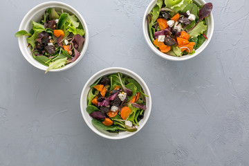 Roasted veggies salad with carrot, beet and cheese in white bowls on grey background, top view 