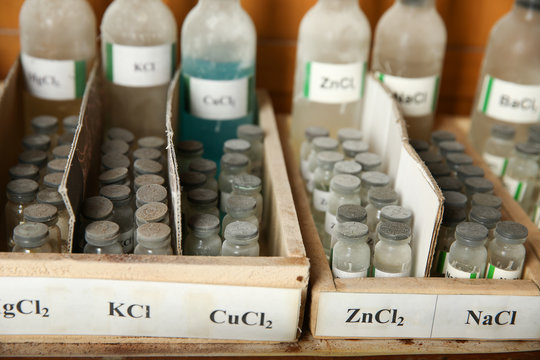 bottles with solutions of KCl, CuCl2, ZnCl2, NaCl on the shelf of the chemical cabinet. Potassium chloride, Copper chloride, Zinc chloride, Sodium chloride are in the bottels