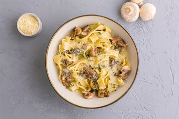 Tagliatelle pasta with mushrooms on grey background, top view