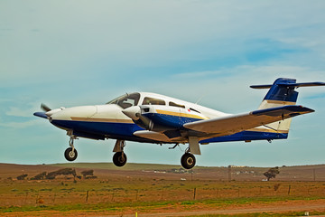 Low flying blue and white twin engine aircraft