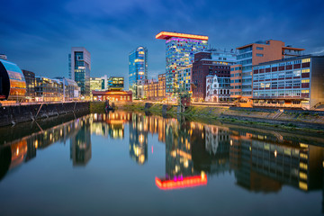 Düsseldorf, Deutschland. Stadtbild von Düsseldorf, Deutschland mit dem Medienhafen und der Spiegelung der Stadt im Rhein, während der blauen Stunde der Dämmerung. © rudi1976