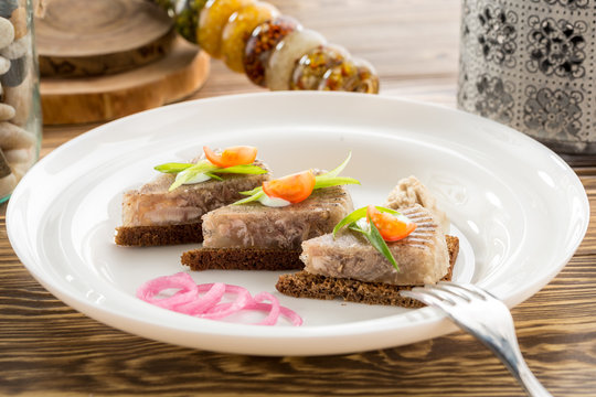 Holodets Homemade jellied meat with garlic and spices garnished with onion on rye bread on wooden table