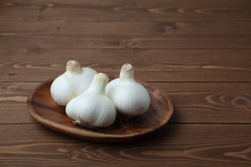 木のテーブルにのせた 生のニンニク ガーリック 木の皿