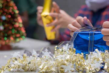 two woman s hands wrapping christmas gift, close up, unprepared chistmas presents on cement table at indoors home park