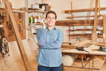 Handwerker Lehrling telefoniert mit dem Handy