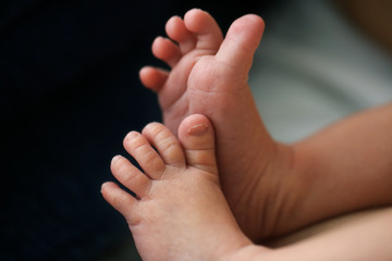 Fototapeta premium Legs and toes of newborn baby on dark