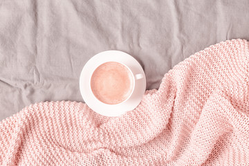 Bed with pink knitted plaid and coffee