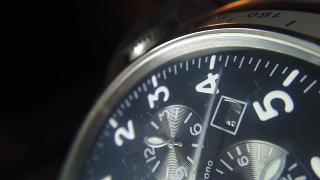 Close up shot of a wrist watch with white clock hands moving.