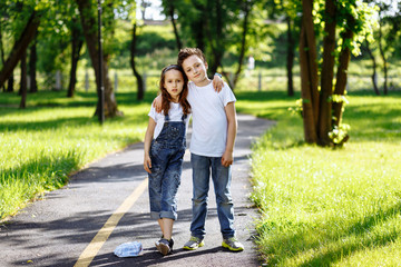 Picture of brother and sister having fun in the summer park on sunset. Cheerful children hugs and laughing. Little girl and boy playing outdoors, best friends, happy family, love and happiness concept