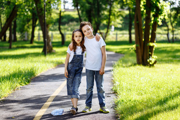 Obraz premium Picture of brother and sister having fun in the summer park on sunset. Cheerful children hugs and laughing. Little girl and boy playing outdoors, best friends, happy family, love and happiness concept