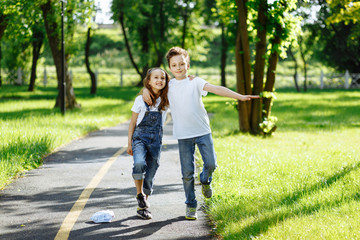 Obraz premium Picture of brother and sister having fun in the summer park on sunset. Cheerful children hugs and laughing. Little girl and boy playing outdoors, best friends, happy family, love and happiness concept